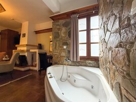 Amplia sala de estar con chimenea de piedra, una bañera grande y un rincón de asientos acogedor.