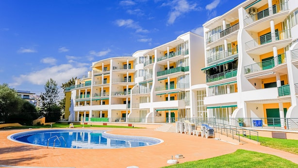 Un hôtel à plusieurs étages, doté de balcons, d’une piscine et d’une pelouse bien entretenue.