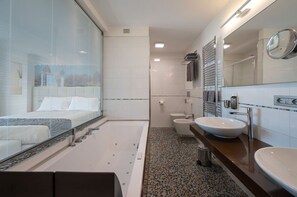 A modern bathroom with a large bathtub, two sinks, a toilet, and a shower.