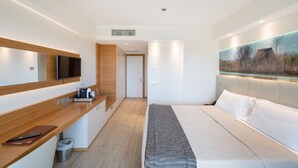 Una habitación de hotel moderna con una cama, un escritorio con una computadora, un televisor y un cuadro de un paisaje.