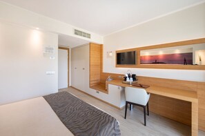 Ein modernes Hotelzimmer mit Bett, Schreibtisch mit Stuhl, Fernseher und großem Fenster mit Sonnenuntergangsblick.