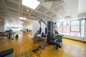 A spacious gym with various exercise equipment, large windows, and a wooden floor. - Zapbed House-ONT 405 (Dubai)