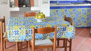 Un coin repas avec une table dressée pour quatre personnes, une cheminée et une cuisine aux carreaux bleus.