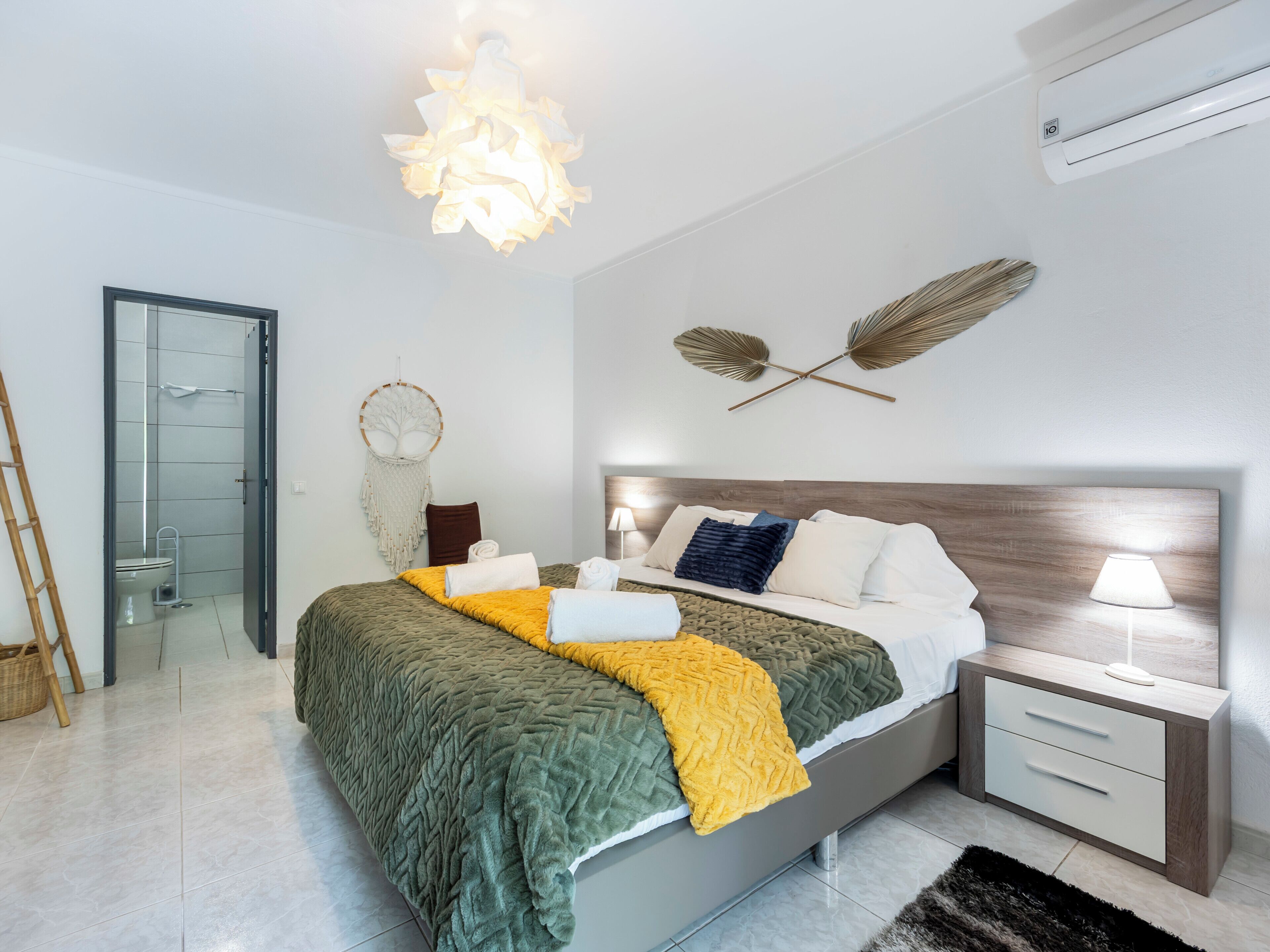 A modern bedroom with a bed, bedside table, wall art, and a hanging light fixture.