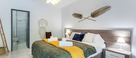 A modern bedroom with a bed, bedside table, wall art, and a hanging light fixture.