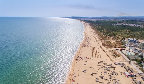 Relax on the beach with sun loungers and umbrellas, surrounded by calm ocean waters and a scenic mountain range.