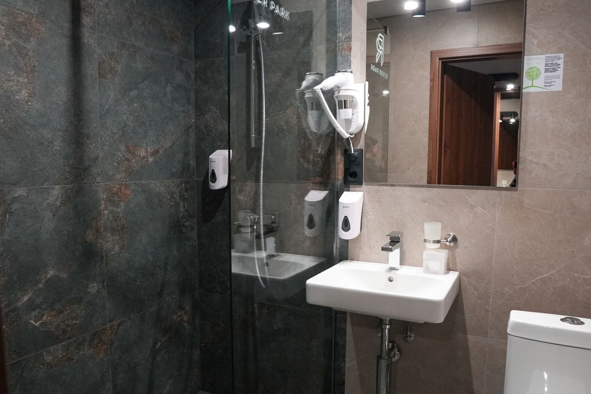 A modern bathroom with a glass-enclosed shower, a white sink, and a toilet.