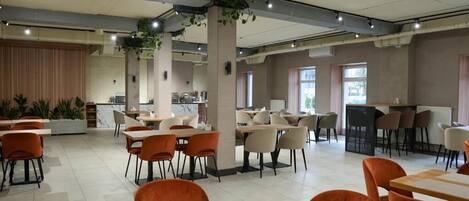 Un restaurante espacioso con varias zonas de comedor, incluyendo un bar y una cocina a la vista.