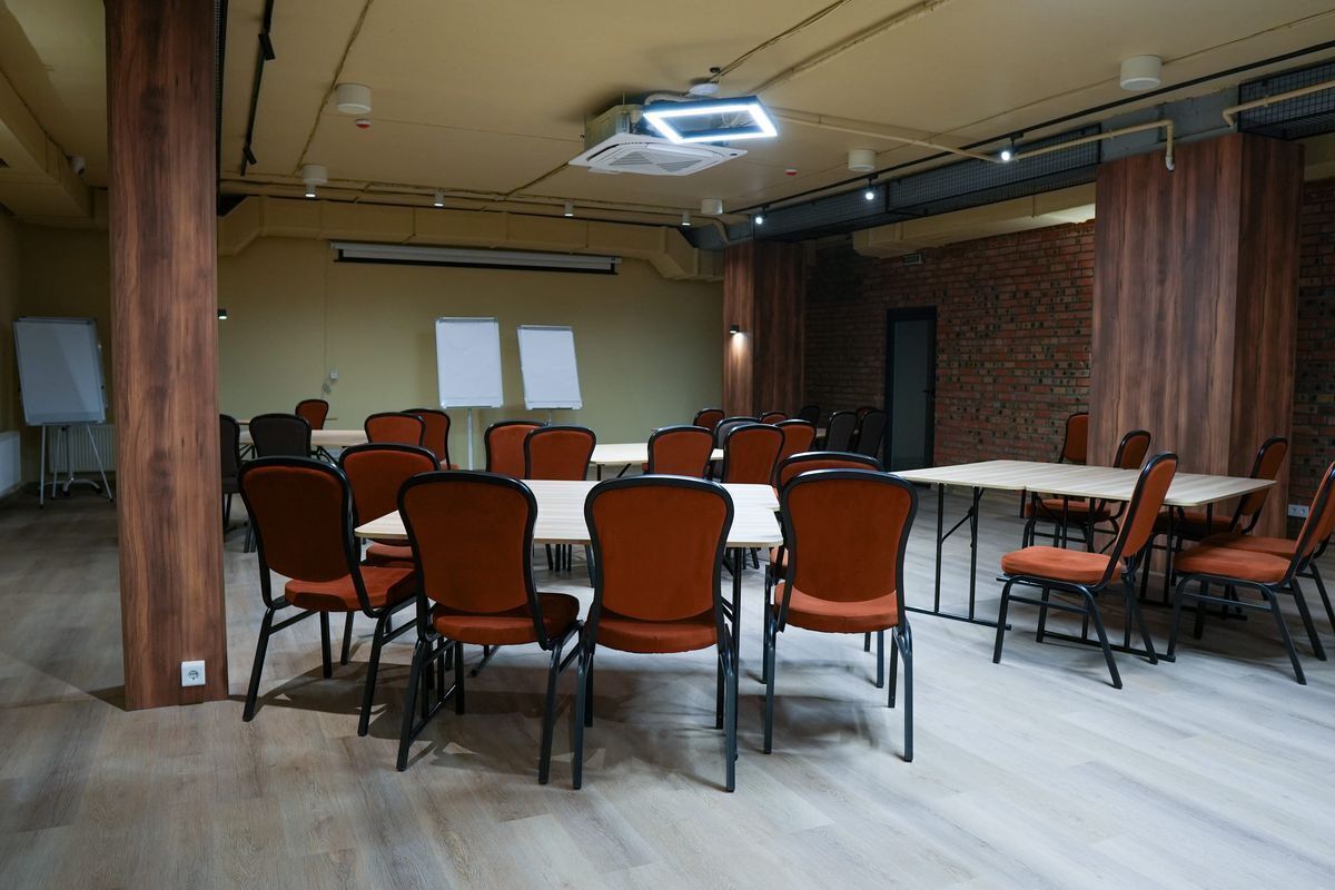 Una sala conferenze con diversi tavoli e sedie, un proiettore e una parete in mattoni.