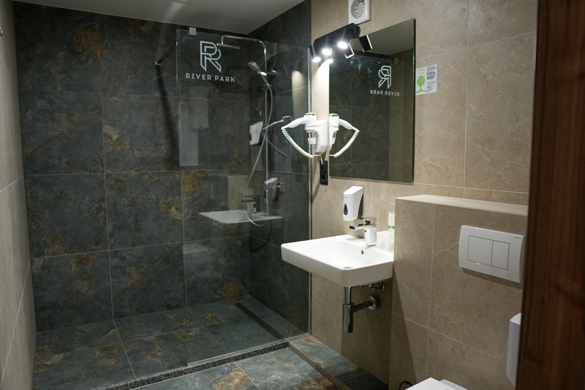 A modern bathroom with a glass-enclosed shower, a white sink, and a mirror above it.
