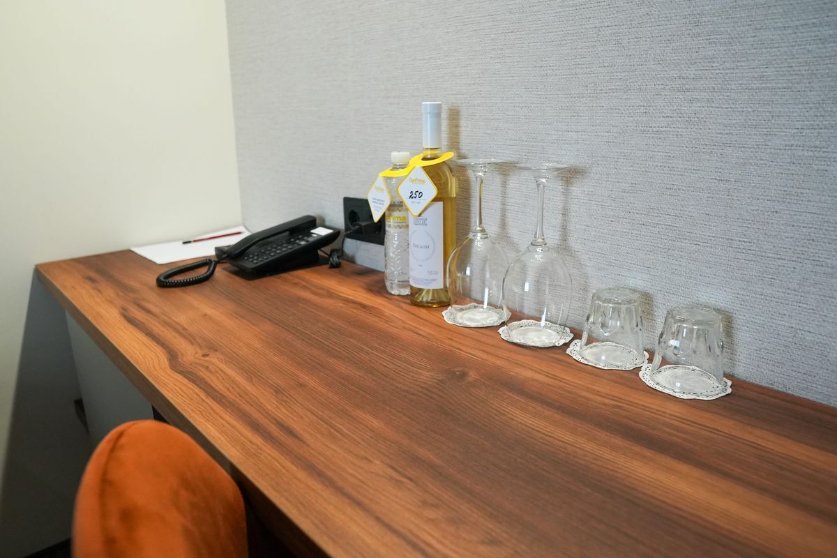 A wooden table with a bottle of wine, wine glasses, and a telephone.