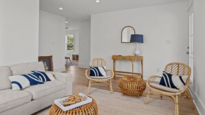 Una sala moderna con un sofá, dos sillones de mimbre, una mesita y una lámpara.
