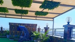 A rooftop garden with artificial grass, potted plants, and a blue slide. - Guiko Palace Hotel  (Douala)