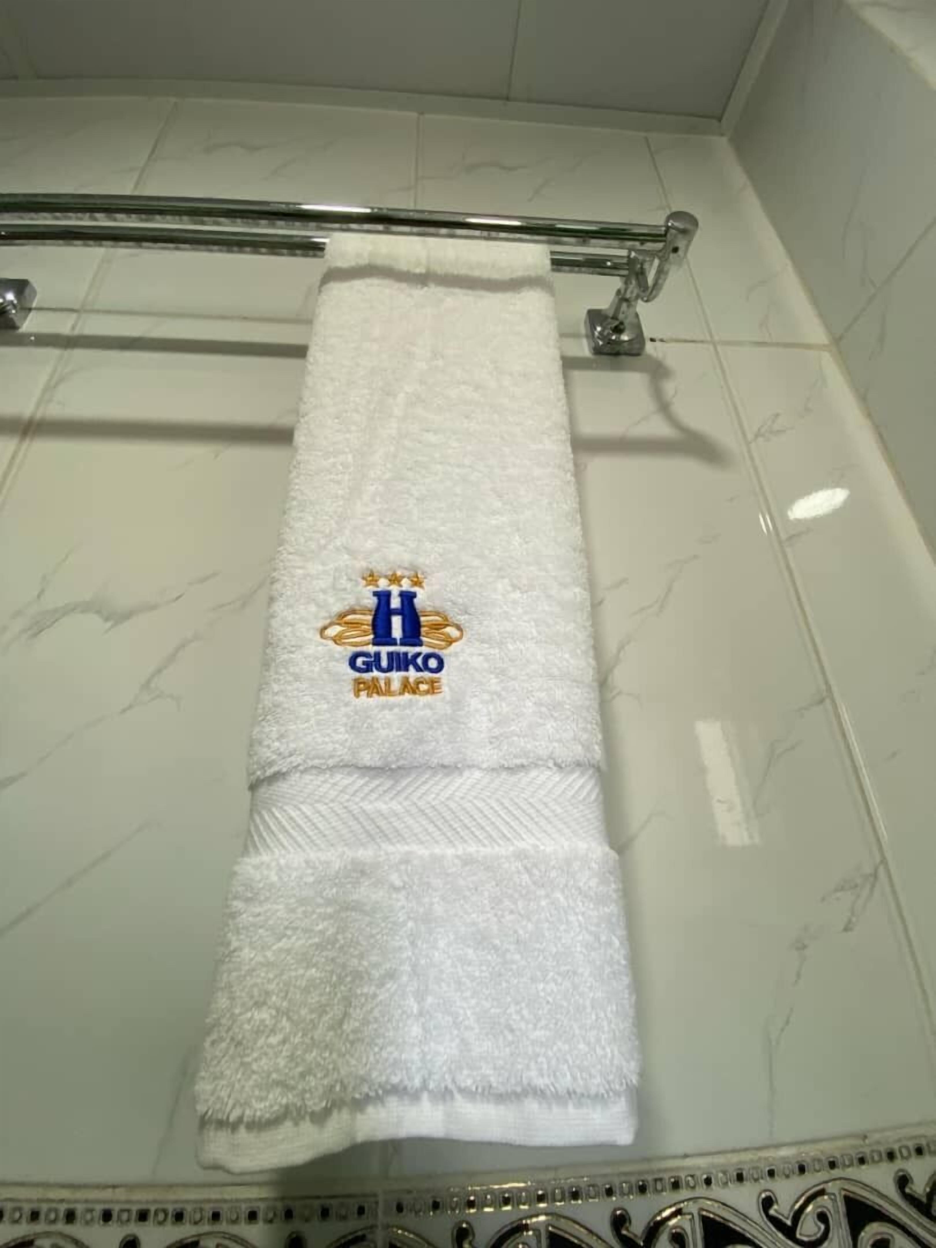 Toalla blanca con logotipo y texto en una pared de baño.