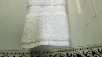 A white towel with a logo and text on a bathroom wall.