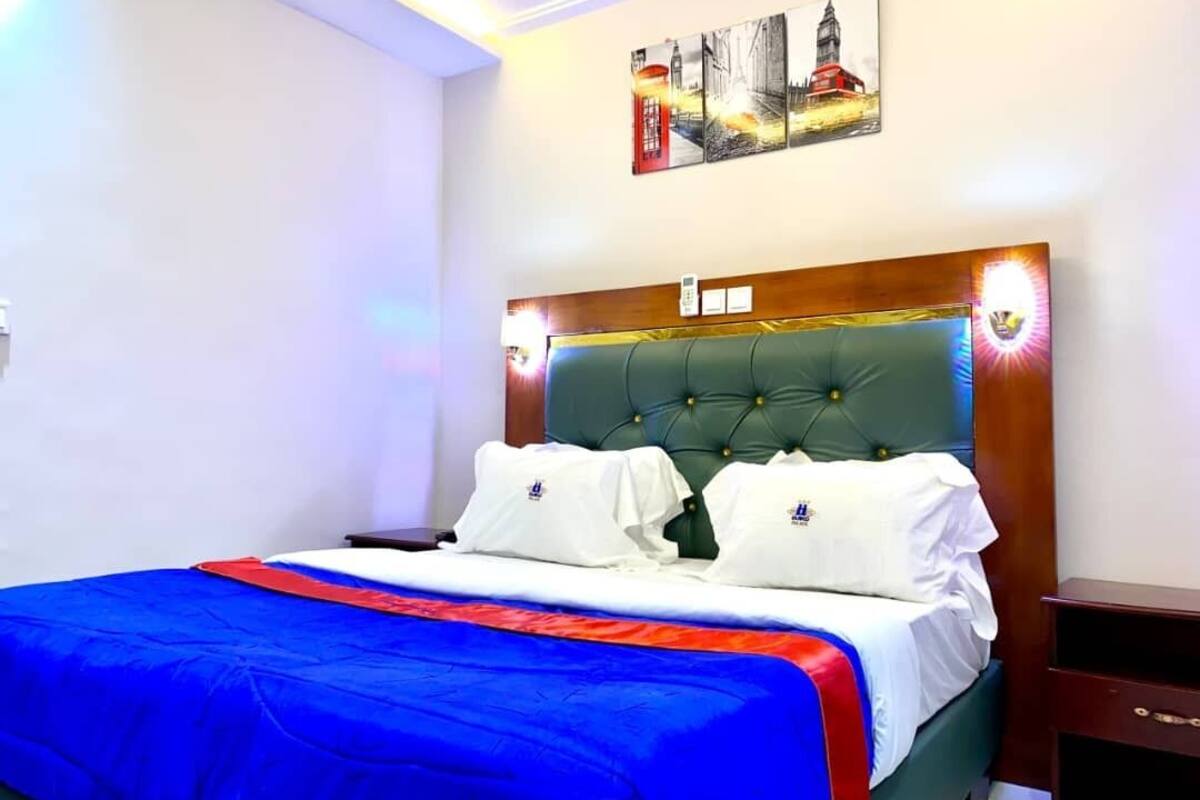A neatly made bed with a green headboard, white pillows, and a blue and red bedspread.