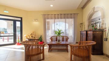 Un coin repas comprenant une table et des chaises, une plante en pot et un meuble contenant des objets décoratifs.