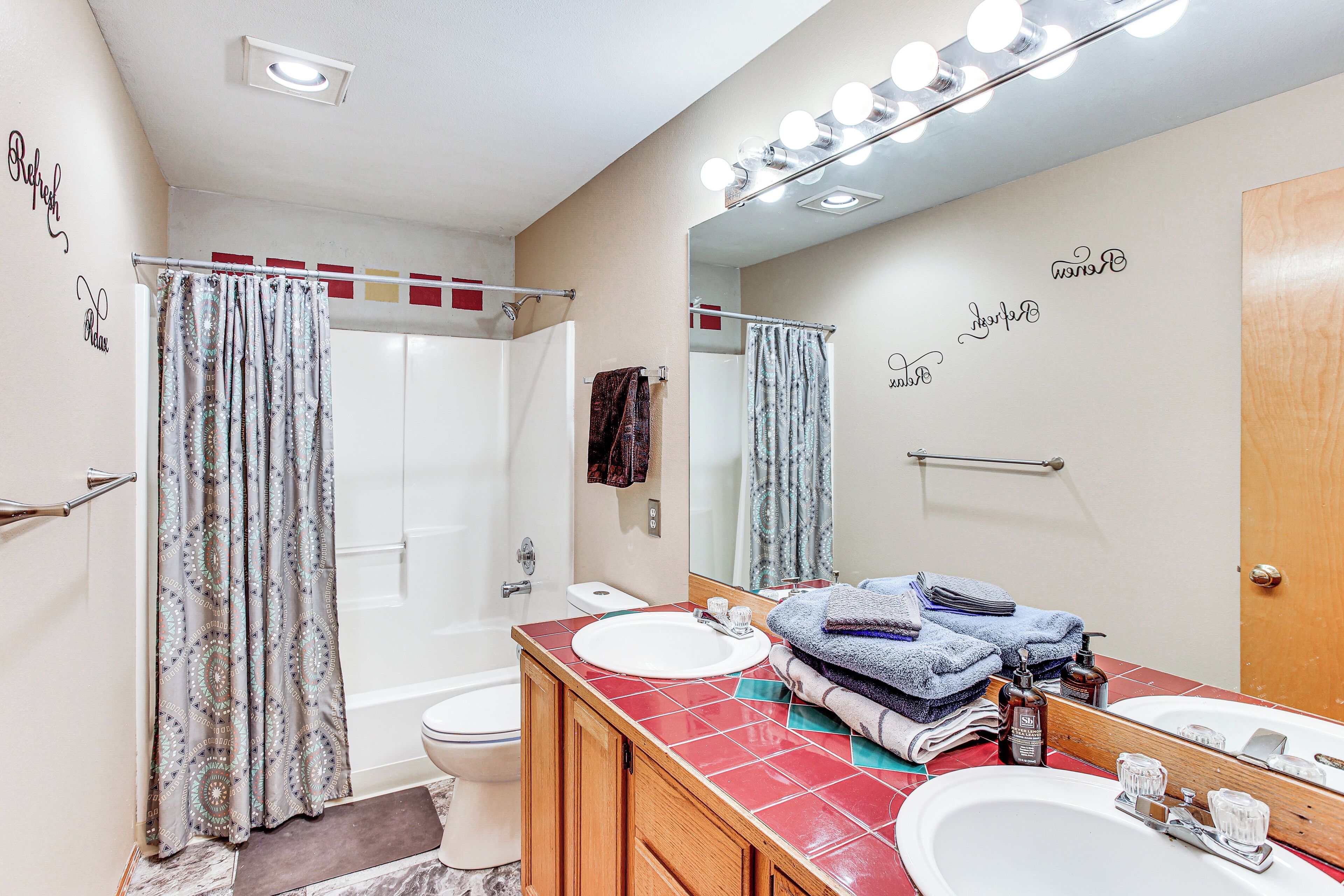 A bathroom with a shower, toilet, and two sinks with a mirror above the sink.