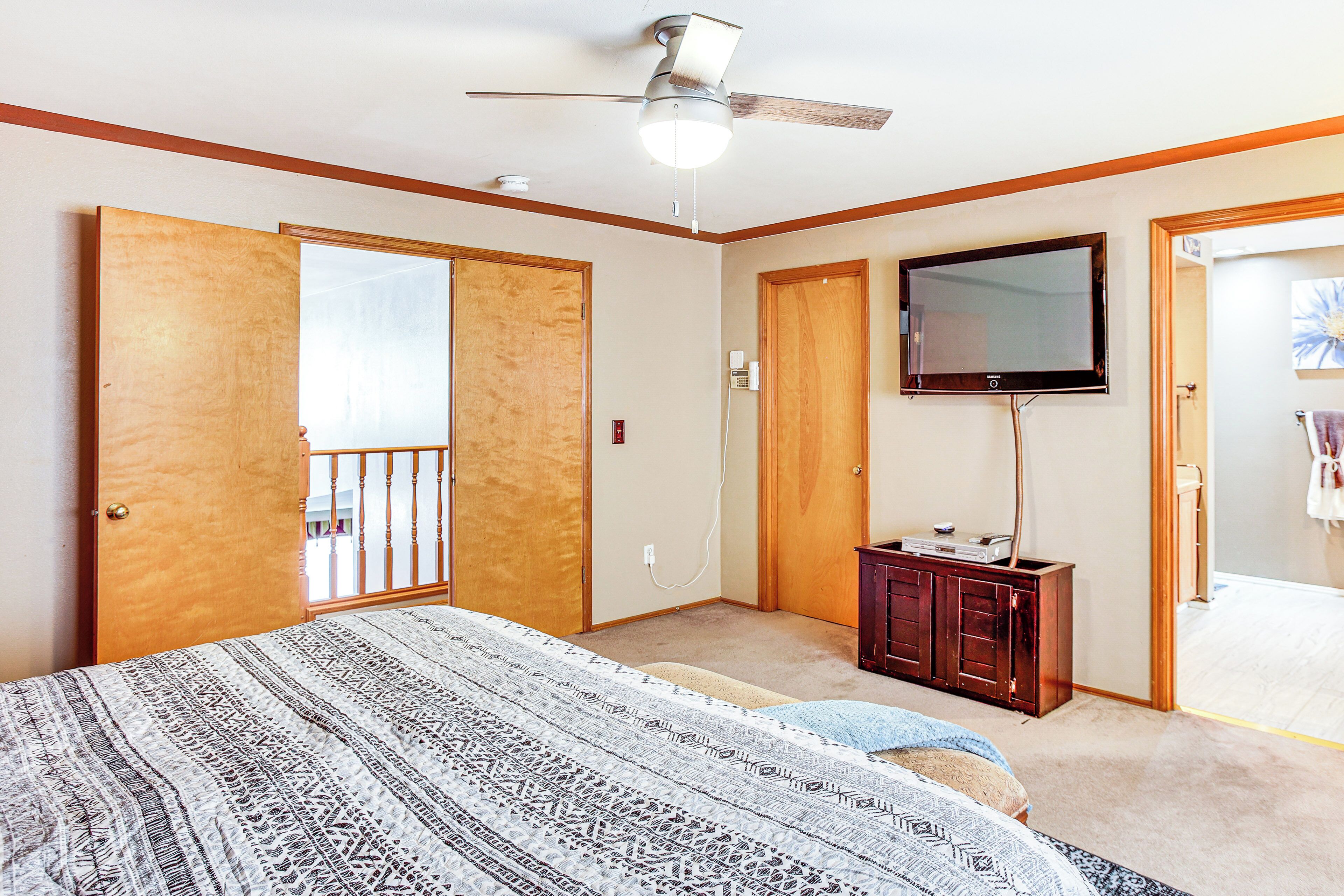 A bedroom with a bed, a ceiling fan, a TV, and a dresser.