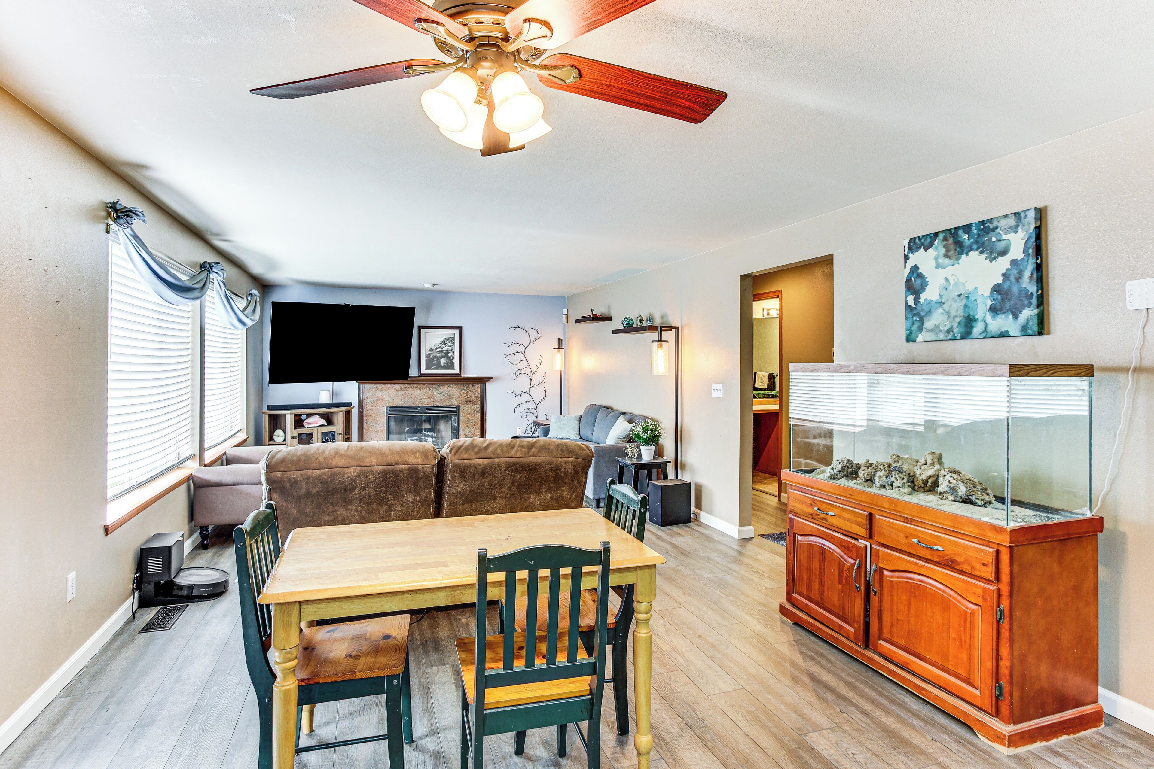 A dining area with a wooden table and chairs, a ceiling fan, and a fish tank.