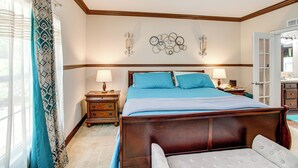 A bedroom with a wooden bed, two bedside tables with lamps, a wall-mounted light fixture, and a door to the right. - 4 Mi to Weston Lake: Eastover Gem (Eastover)