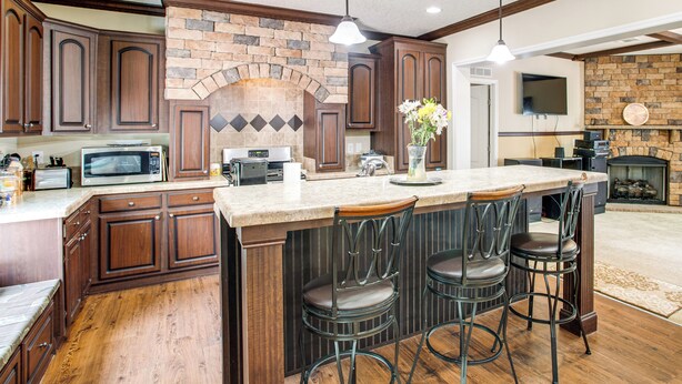 A kitchen with wooden cabinets, a stone backsplash, a built-in microwave, and a large island with bar stools. - 4 Mi to Weston Lake: Eastover Gem (Eastover)