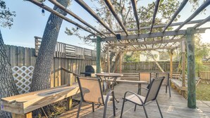 An outdoor wooden deck with a pergola, seating area, and a grill.