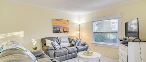A living room with a sofa, a coffee table, a lamp, and a TV.