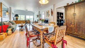 A spacious living room with a wooden dining table, comfortable seating, and a large cabinet. - Artsy Bungalow on St Anne Lake: Pool, Dock & Deck (Lake Wales)