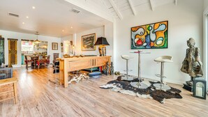 A spacious living area with a wooden floor, a central island with stools, a cowhide rug, and a Buddha statue. - Artsy Bungalow on St Anne Lake: Pool, Dock & Deck (Lake Wales)