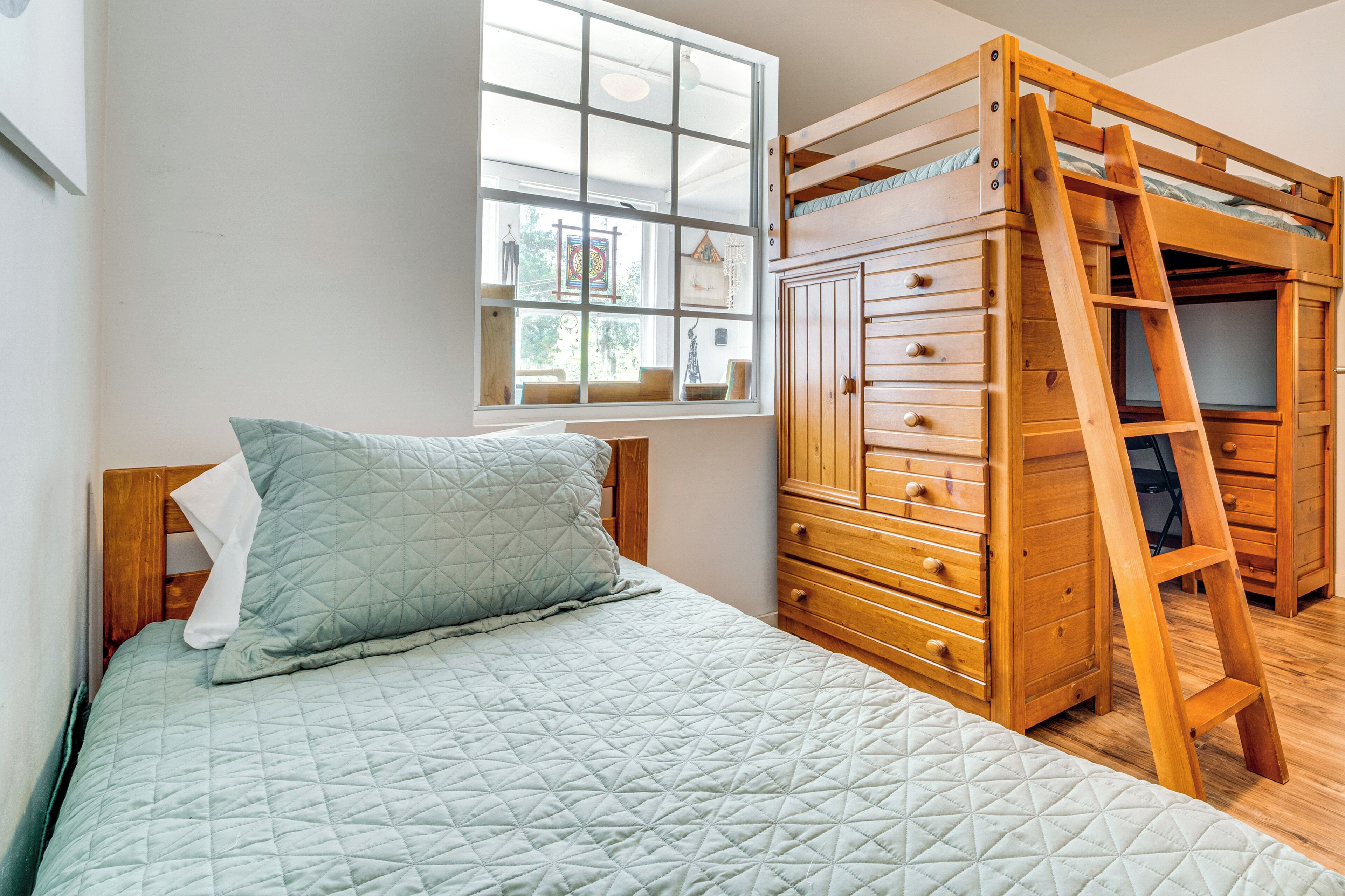 Un dormitorio con una cama, una ventana con vistas y un aparador de madera con cajones.