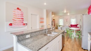 A modern kitchen with granite countertops, a double sink, and a dining area with a round table and green chairs. - 2 Mi to TBK Bank Sports Complex: Townhome w/ Patio (Bettendorf)