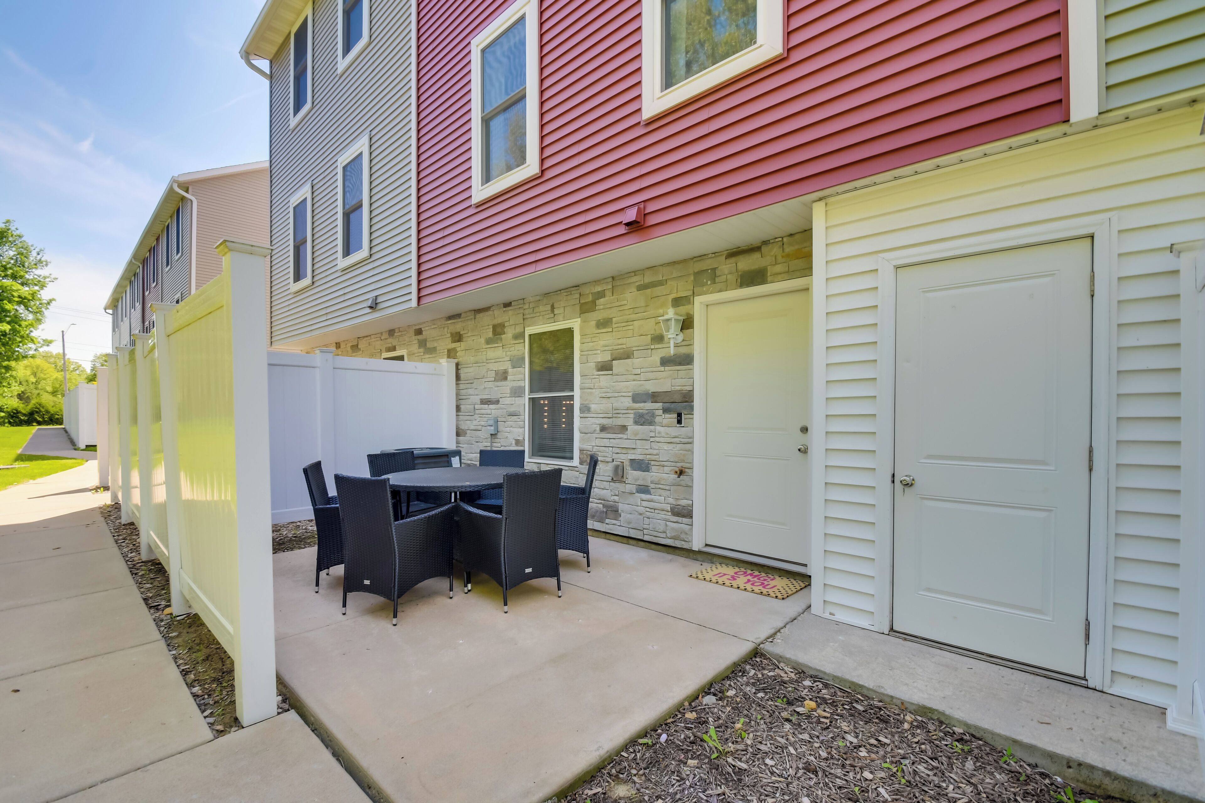 A residential exterior with a patio, a white garage door, and a stone wall.