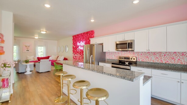 A modern kitchen with white cabinets, stainless steel appliances, and a pink floral accent wall. - 2 Mi to TBK Bank Sports Complex: Townhome w/ Patio (Bettendorf)