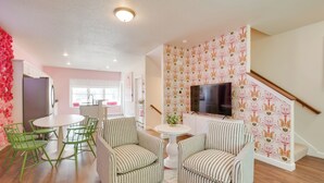 A living room with a TV, striped chairs, a round table, and a staircase. - 2 Mi to TBK Bank Sports Complex: Townhome w/ Patio (Bettendorf)