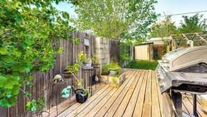 Eine Holzterrasse mit Grill, Blumentöpfen und einem Holzzaun.