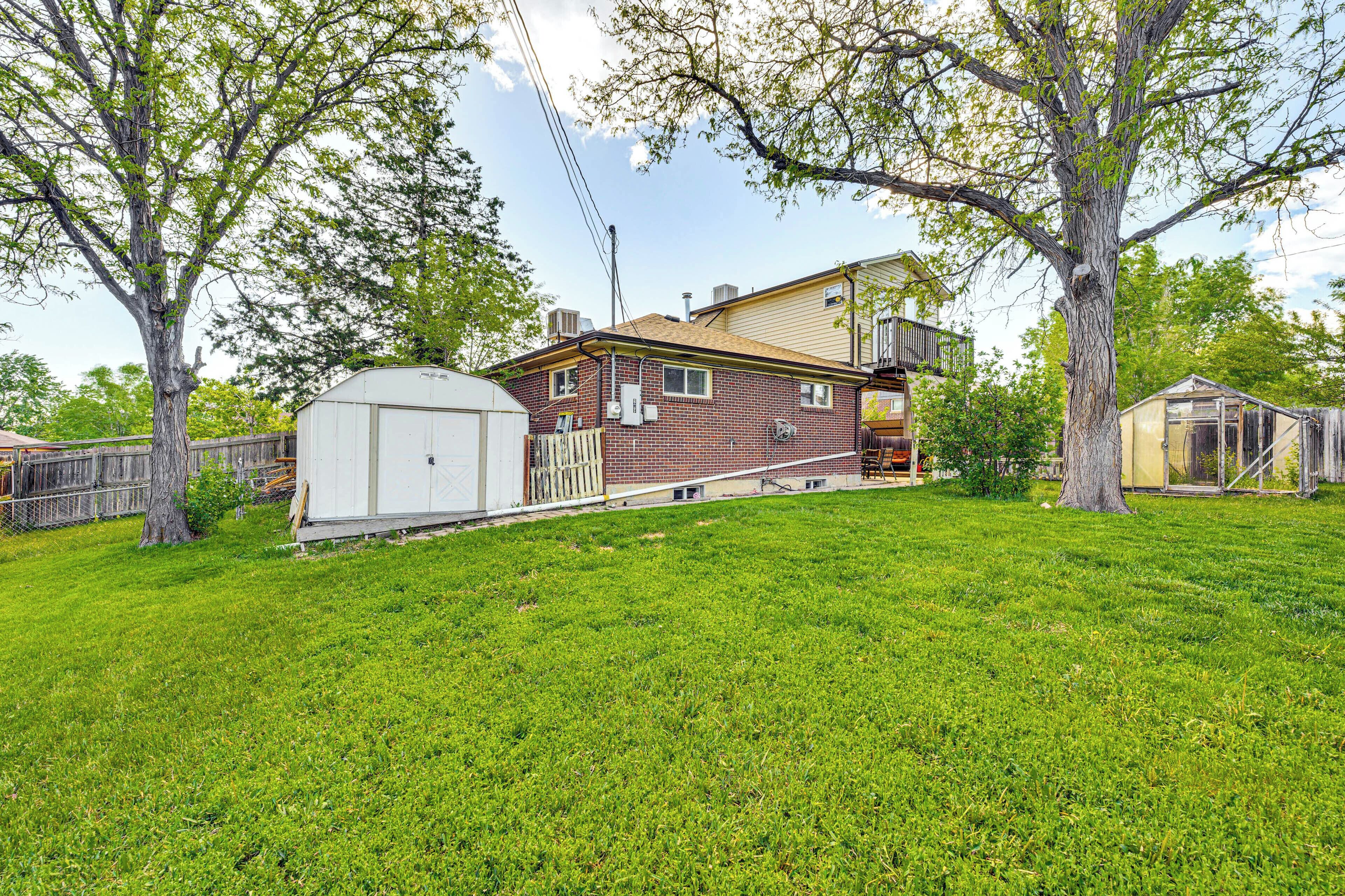 A single-story house with a brick exterior, a small attached garage, and a large tree in the front yard.