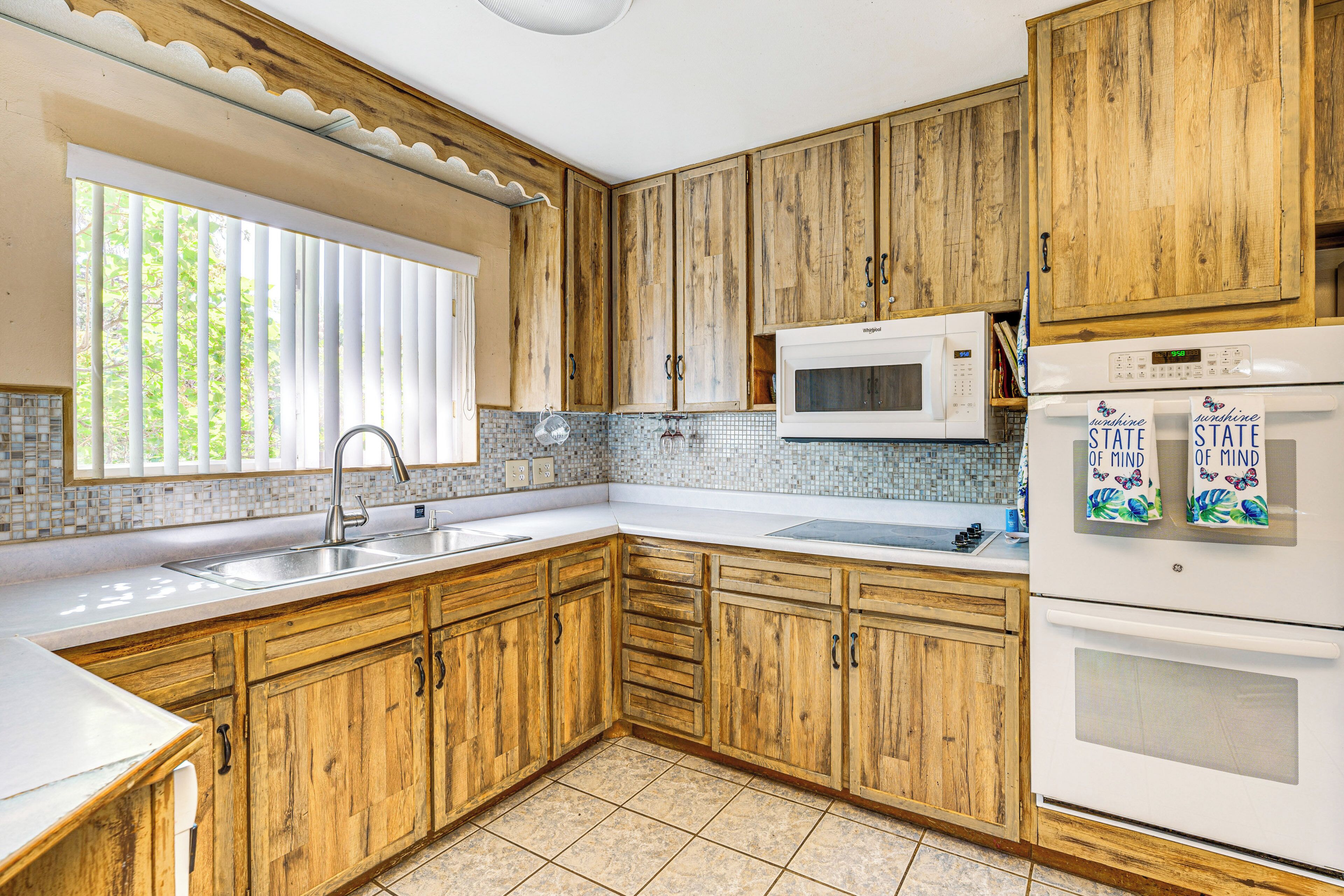 A kitchen with wooden cabinets, a white countertop, a sink, a microwave, and a refrigerator.