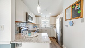 Una cocina moderna con encimeras de granito, electrodomésticos de acero inoxidable y una isla central con lavamanos.