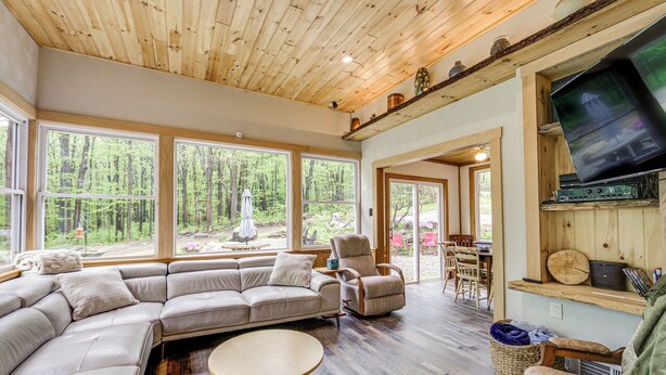 A spacious living room with a large sectional sofa, a round coffee table, and a television mounted on a wooden wall.