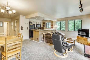 Relax in this open-plan living area with a dining table, comfortable seating, and a modern kitchen.