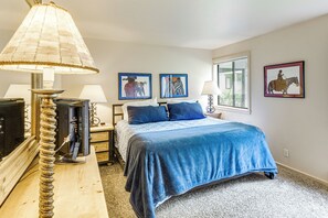 Relax in a serene bedroom with a large bed, classic lamp, and beautiful views of the surrounding greenery.