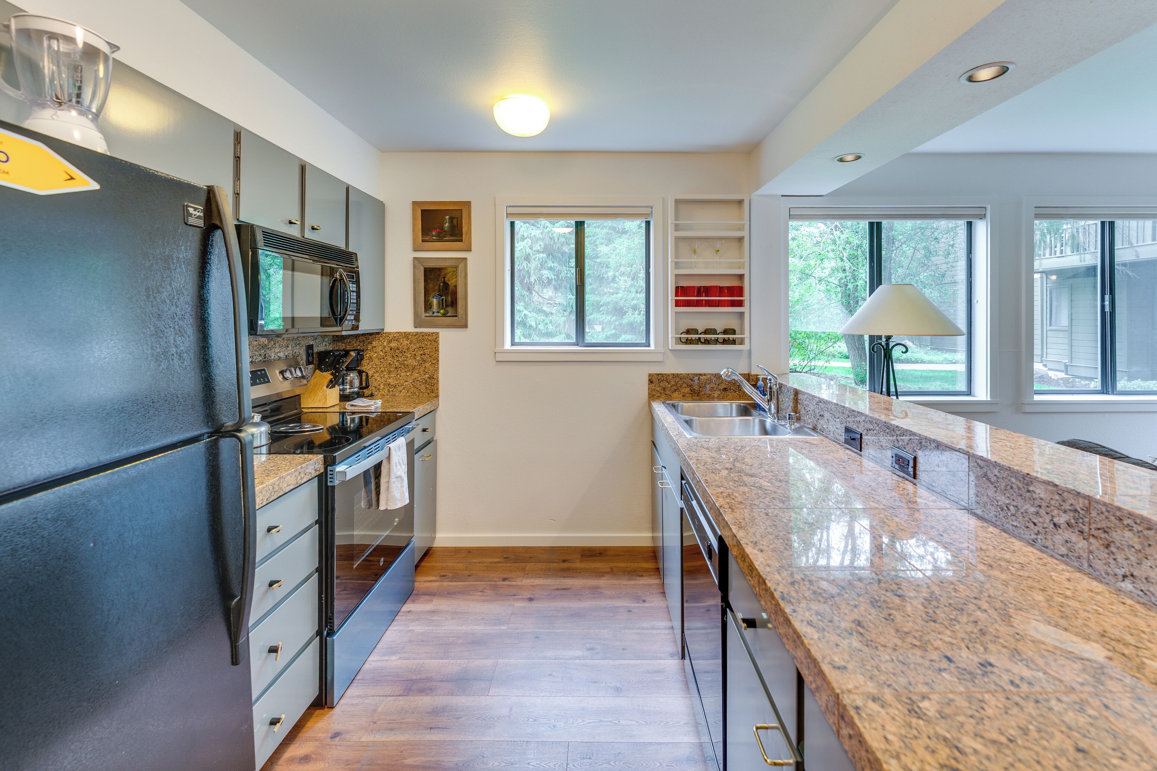 A modern kitchen with granite countertops, stainless steel appliances, and a window providing natural light.