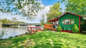 A green house with a porch, a small deck, and a view of a lake. - 'crater Lake' Williamson River Resort Cabin 6 (Chiloquin)