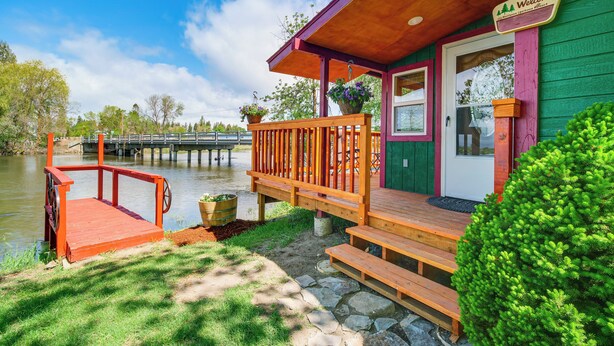 A wooden dock extending into a calm body of water, a green building with a porch, and a 'Welcome' sign. - 'crater Lake' Williamson River Resort Cabin 6 (Chiloquin)