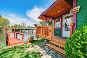A wooden dock extending into a calm body of water, a green building with a porch, and a 'Welcome' sign. - 'crater Lake' Williamson River Resort Cabin 6 (Chiloquin)