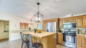 Una cocina con una isla central, electrodomésticos de acero inoxidable, armarios de madera y un candelabro.
