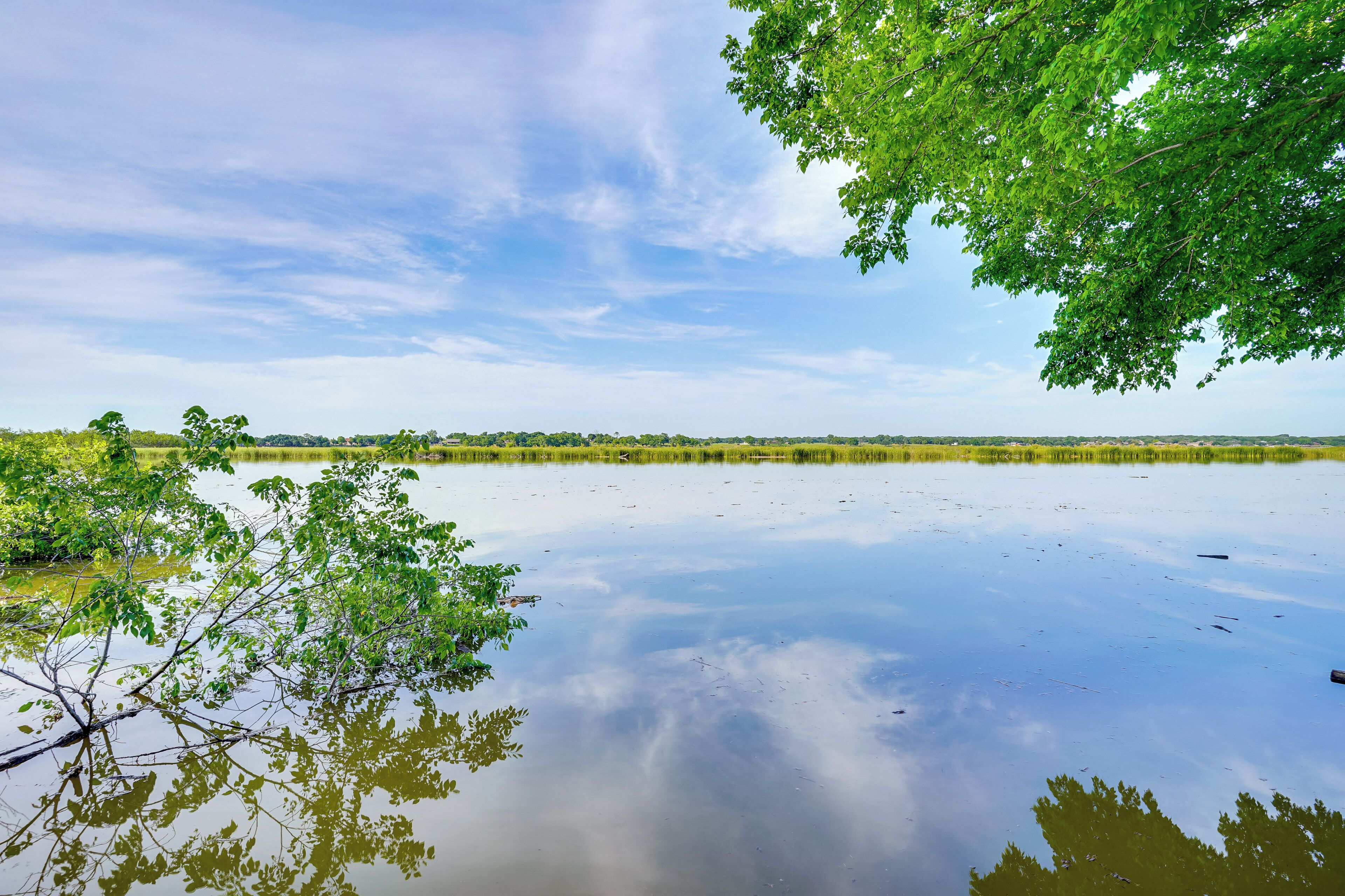 A calm lake with reflections of trees and a clear sky.
