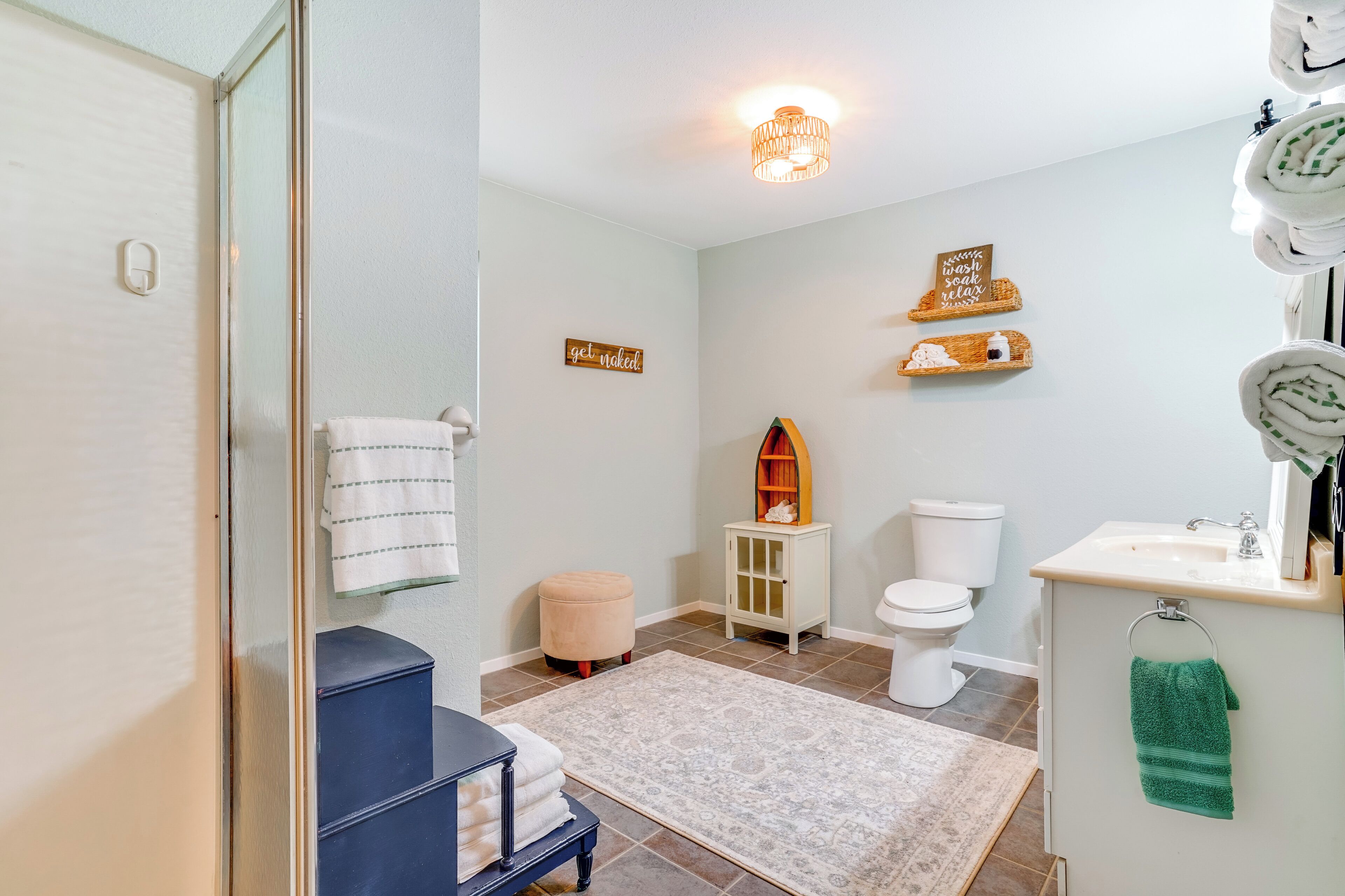 Une salle de bain moderne avec une douche à parois de verre, des toilettes blanches, un lavabo avec un miroir et un petit meuble en bois.