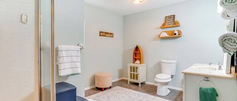 Une salle de bain moderne avec une douche à parois de verre, des toilettes blanches, un lavabo avec un miroir et un petit meuble en bois.